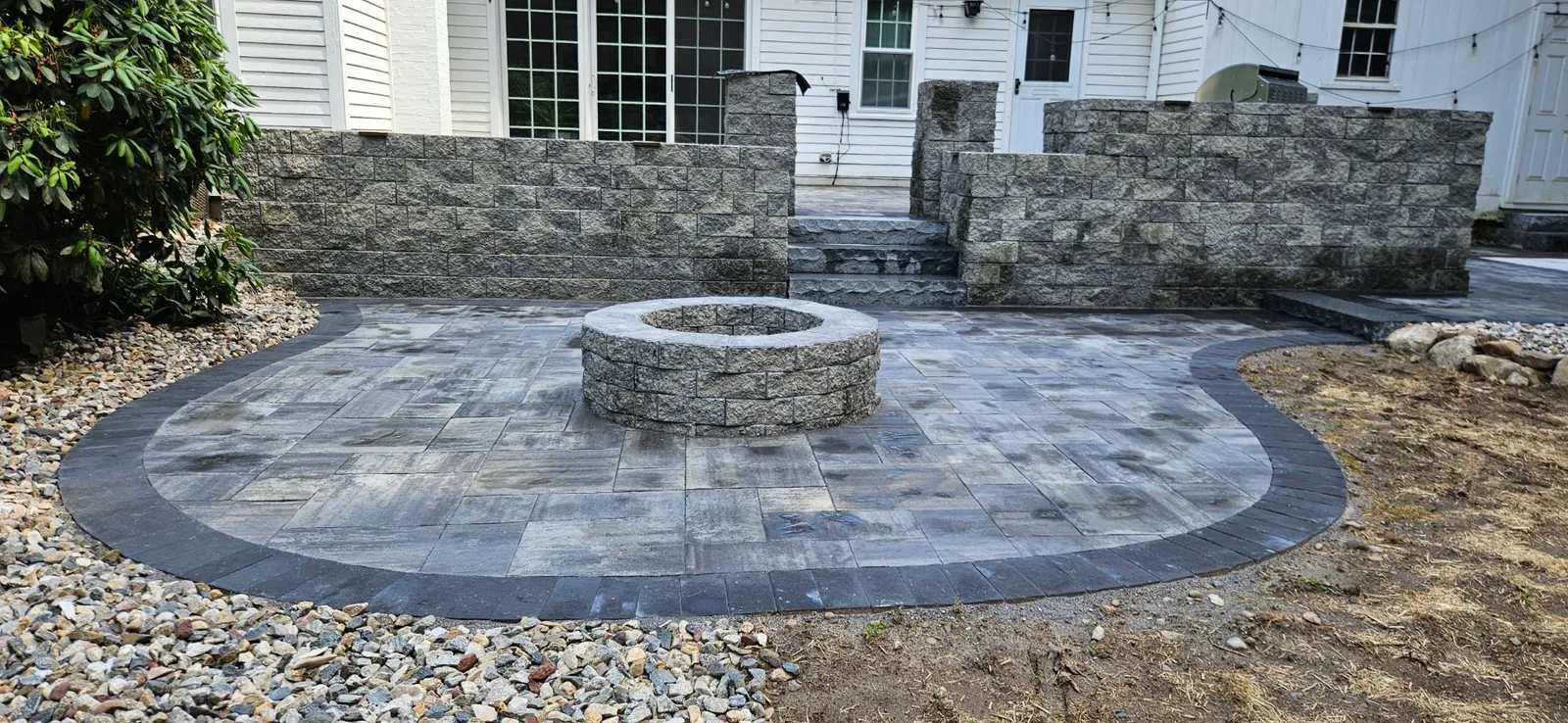 Paver patio with firepit and seating wall built by Stone & Scappes